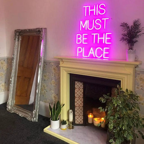 This Must Be The Place Neon Sign Dimmable Light Decor For Bedroom Man Cave Shop Salon Office Decoration Hot Pink Bright Yet Subtle Neon Artwork For Dope Vibe And Cozy Ambience above a fireplace next to a mirror.