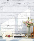 Peel And Stick Wood Shiplap Wallpaper In Light Grey White And Blue Distressed Planks behind a vase with flowers on a table