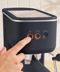 Hand pressing button on 20 Bar Slim Espresso Maker With 1300 Watt Pump And 360 Degree Steam Wand For Silky Microfoam.