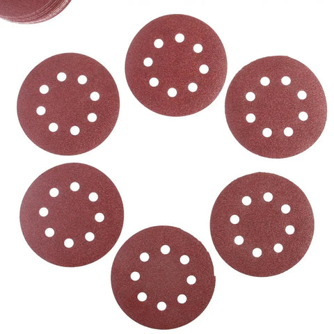 Super Tough 5 Inch Hook And Loop Sanding Discs With Eight Holes For Dustless Vibes arranged on a flat surface, showing fine alumina grain.