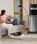 Person pouring water next to dispenser with non-slip silicone water cooler mat with raised edge for floor protection 22x19 inches