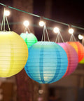 Multicolor 48 Pack Paper Lanterns For Parties Round Chinese Style Hanging Lamps In 4, 6, 8, And 10 Inch Sizes Easy To Fold And Store Durable Party Decor For Graduation Wedding Birthday Bridal Shower And Other Celebrations hanging at night, close-up view.