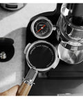 Premium Double Layer Reusable Espresso Shower Screen Filter For 51mm Portafilter Plus 304 Stainless Steel Bottomless Filter Kit held above espresso machine.