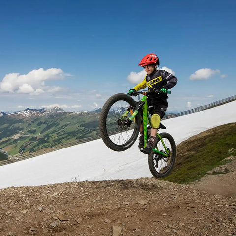 Kid performs a wheelie on a mountain bike, showcasing Speedrun Junior Mountain Bike Handlebar With Bar Clamp 31.8mm, 680mm Width.