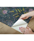 Hands peeling back Purple Dandelion Peel And Stick Wallpaper Roll Removable No Residue 20.5 Inch Wide By 16.5 Feet Long