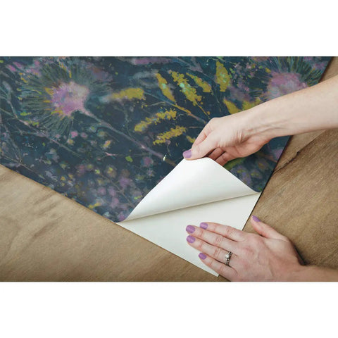Hands peeling back Purple Dandelion Peel And Stick Wallpaper Roll Removable No Residue 20.5 Inch Wide By 16.5 Feet Long