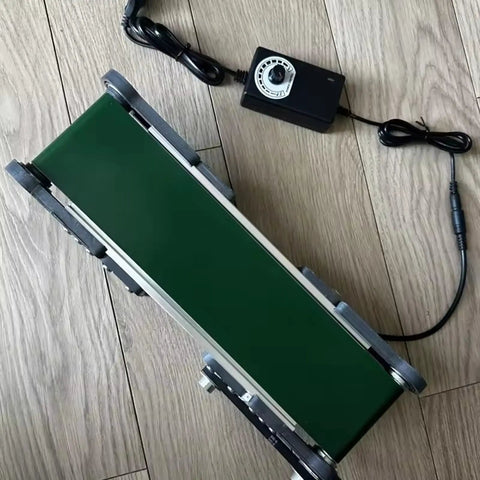 Top view of Mini Electric Desktop Conveyor Belt For DIY Projects And Friction Experiments next to its control module on wooden floor
