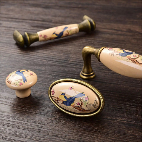 4 Pack Ceramic Cabinet Knob Pulls Set For Cabinets And Dressers, Durable Rust-Resistant Metal Handles with bird design on wood table.