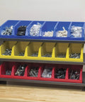 Garage Ready Heavy Duty Three Shelf Work Bench Storage Rack With Angled Shelves For Plastic Bins, 36 And Three Quarters Inches Wide, 12 Inches Deep, 25 Inches High, Gray, loaded with sorted hardware bins on a wooden table.