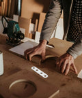 Carpenter using heavy duty stainless steel shelf brackets set with four hole flat brackets and 120 screws in workshop.