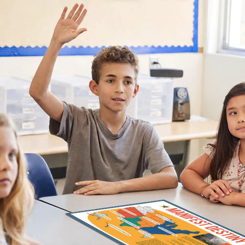 Student raising hand in classroom with 5 Poster Set On American Expansion In US History For Classrooms visible on table