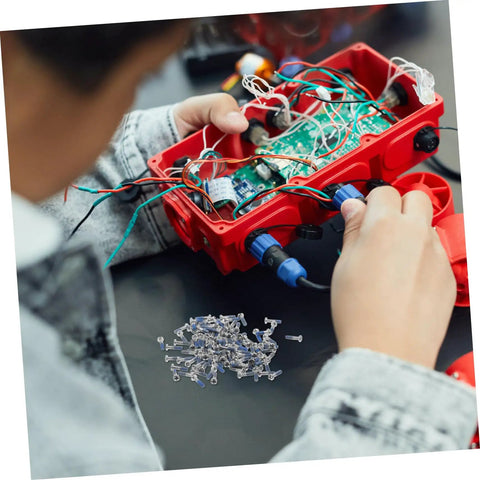 Person working on electronics with scattered screws from a Glasses Repair Screws Kit, 100 Piece Eyeglass Screw Set For Glasses And Sunglasses.
