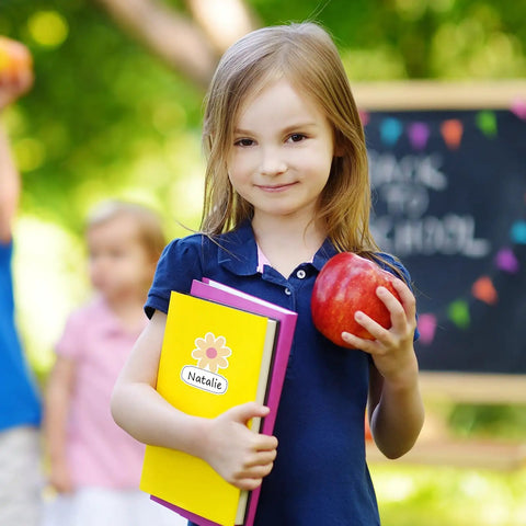 Child holding book with Retro Groovy Floral Name Tag Stickers With Daisy Flower Nameplates for back to school scene