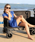 Person sitting on Heavy Duty Folding Wagon Cart With Wheels 560Lbs Load 240L Capacity 3 In 1 Gear Hauler Beach Wagon Chair on beach