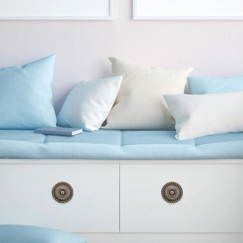 Vintage Round Cabinet Knobs Set Of 10 With Antique Copper Finish on white drawers below blue and white cushions