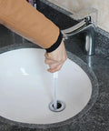 Hand using Sink Drain Overflow Cleaning Brush 17.7 Inch Long Flexible Hair Catcher in bathroom sink drain