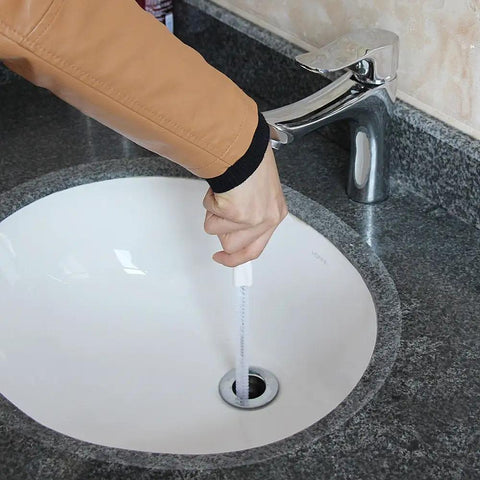 Hand using Sink Drain Overflow Cleaning Brush 17.7 Inch Long Flexible Hair Catcher in bathroom sink drain