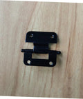 Front view of black metal cabinet hinge with mounting plates on wood surface