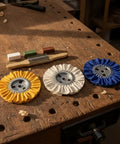 KQFCAZRE 3 Pc Cloth Polishing Wheel Kit with Buffing Agent, yellow, white, blue pleated buff wheels on workbench.