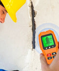 Man using Wall Stud Finder Scanner LCD Display Electric Portable on wall crack, showing detection mode on screen.