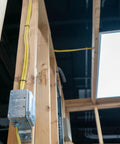 SimPull Solid Indoor 12 2 NM B Wire With Ground 50ft Coil for Residential Wiring running through wooden frame indoors.