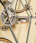 Wall Mounted Bike Rack With Bamboo Shelf For Indoor Storage And Decor holding a bicycle and decor against a beige wall