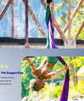 Person performing aerial dance using purple silk rigging against outdoor industrial backdrop
