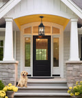 Badass Matte Black Outdoor Pendant Lighting Three Bulb Exterior Hanging Porch Fixture With Clear Glass Shades All Weather Housing For A Seamless Front Step Glow Up above a front door with yellow accents and a dog.
