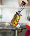 Hand lifting jar from pot using 12 inch stainless steel canning rack with contour handles for pressure canner pot.