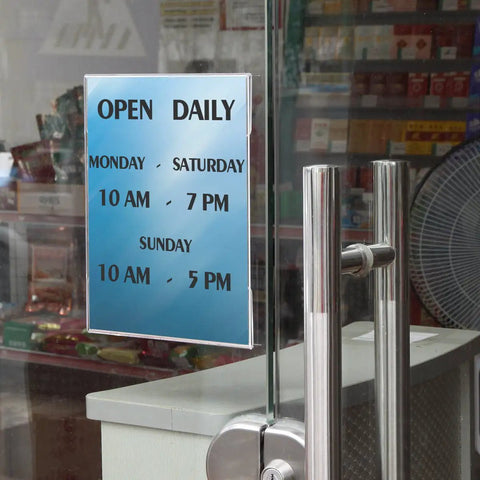 8.5x11 Clear Acrylic Sign Holders With No Drilling Mount displaying store hours on glass door
