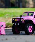 Pink Jeep Wrangler 1:16 RC Car for Kids with 2.4GHz remote control on pavement, outdoor setting