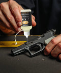 Applying All In One Gun Lube And Cleaner Kit With Two Oz And One Oz Needle Oiler For Quick Cleaning on a firearm slide