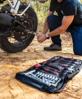 Rider using Adventure Motorcycle Tool Kit 40 Piece Compact Tool Roll For Dual Sport And Adventure Bikes on rear wheel in dirt