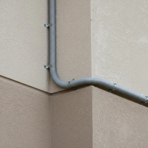 Ironclad Flex Gray Conduit 64mm X 10M Thickened Wire Cable Protector Sleeve installed at a corner on wall for electrical wiring.