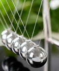 Cradle Balance Pendulum Balls Set With Black Base showing five metal balls suspended on nylon strings, close-up view.