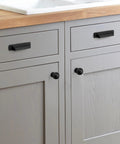 Six Pack Matte Black Cup Drawer Pulls 3 Inch Center To Center Cabinet Hardware installed on gray kitchen cabinets.