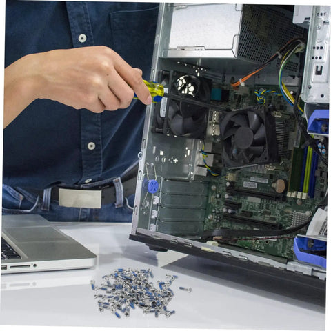 Person repairing computer with screwdriver, pile of screws in foreground, open computer case with visible components.