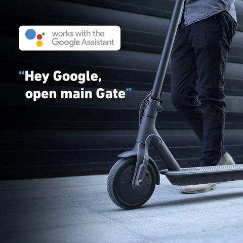 Person standing near scooter with 'Works with Google Assistant' text, showcasing Smart Gate Opener Lite With App Control And Wireless Sensor.