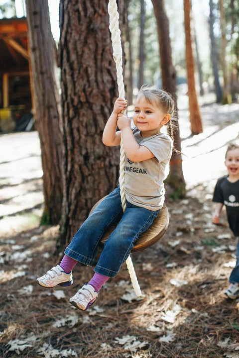 Child playing on Drifter Zip Line Seat For Kids And Adults Built To Last Heavy Duty Wooden Seat Steel Lock Carabiner Adjustable Nylon Rope