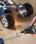 Variable Speed Corded Rotary Tool Kit for DIYers cutting metal rod near toy car, sparks flying