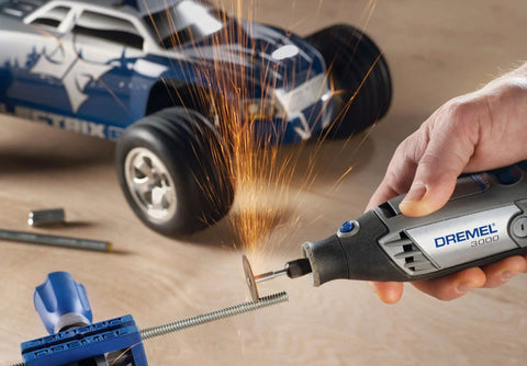 Variable Speed Corded Rotary Tool Kit for DIYers cutting metal rod near toy car, sparks flying