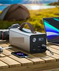 Rugged Portable Power Station With 200W Output for Trail Camping and Emergency Prep near laptop and camera on wooden table.