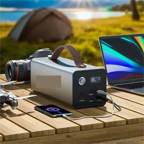 Rugged Portable Power Station With 200W Output for Trail Camping and Emergency Prep near laptop and camera on wooden table.