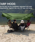 People sitting under UltraLight 11 Ft Hammock Shelter with Net and Rain Fly Tarp Four In One Camping Tent at a beach.