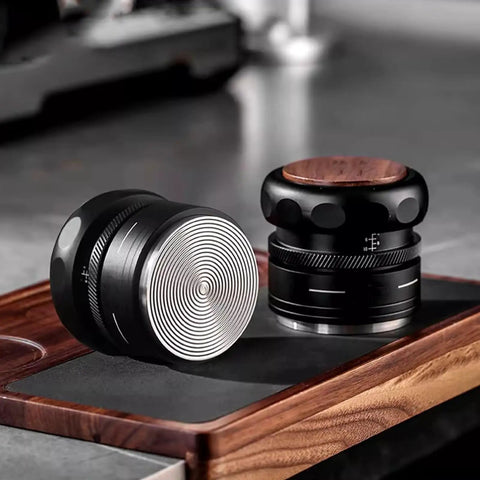 Two coffee tampers on a wooden mat, featuring a round steel base and ergonomic design, part of the Slick Espresso Tamper Set For 58Mm Portafilters With Auto Scale Dial Wdt Tool And Smart Storage Mat A Fire Four Piece Kit That Straight Up Upgrades Your Daily Coffee Grind Game.