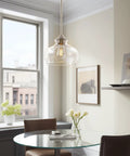 Modern Schoolhouse Pendant Light With Clear Glass Shade In Brushed Nickel Finish above dining table in bright room.