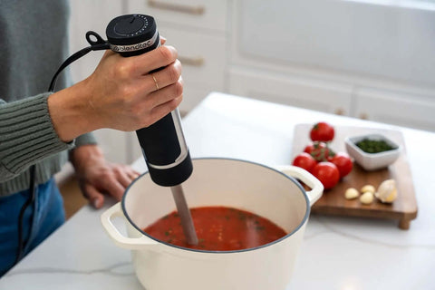 Professional Grade Commercial Blending Machine With A Badass 1800 Watt Motor And Dead Simple Variable Speed Settings For Top Shelf Bar Mixes And Cafe Kitchens In Rust Proof Stainless Steel mixing tomato sauce in a pot.