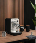 Next Level Semi Pro Espresso Machine Featuring 15 Bar Pump Pressure And Triple Thermoblock Heating For Rock Solid Temp Control And Strong Steam Wand Pulling Real Deal Barista Shots Daily In Glossy Black on a wooden table.