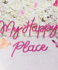 Pink LED Neon Light Sign My Happy Place Two Panel Wall Decor For Home Bar Bedroom Living Room Kid Room Wedding Gift 12V Power Adapter Included Bright Fun Glow That Feels Cozy And Cool in front of flower wall.