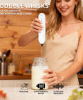 Woman using Two Pack Handheld Milk Frother With Stand For Lattes Cappuccinos Matcha And Hot Chocolate Go To Valentines Day Gift For Him And Her Black And White to froth milk in a jar, creating smooth microfoam in a kitchen setting.